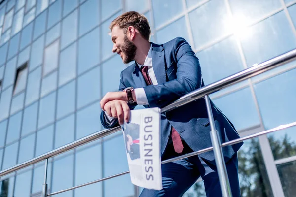 Businessman with newspaper at office building — Stock Photo