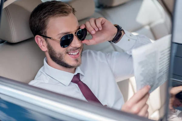 Geschäftsmann liest Zeitung auf dem Rücksitz des Autos — Stockfoto