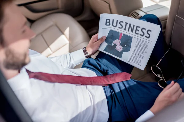 Mann mit Wirtschaftszeitung auf dem Rücksitz des Autos — Stockfoto