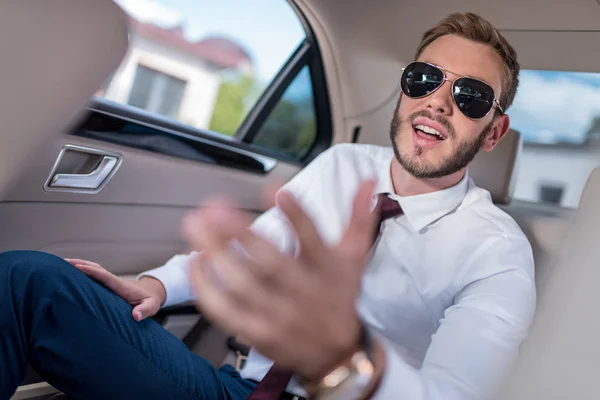 Businessman in sunglasses on backseat of car — Stock Photo