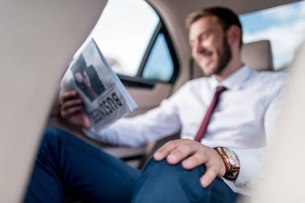 Hombre con periódico en el asiento trasero del coche - foto de stock