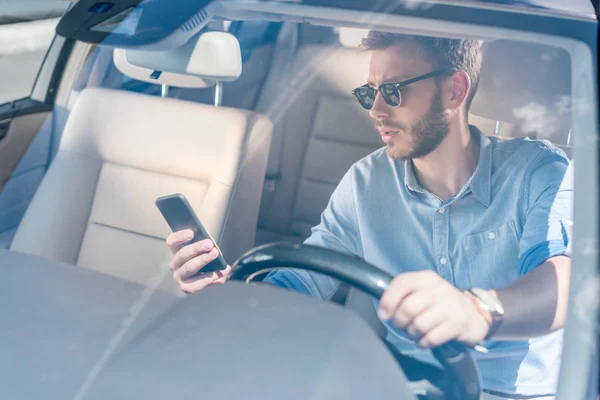 Homme avec smartphone voiture de conduite — Photo de stock