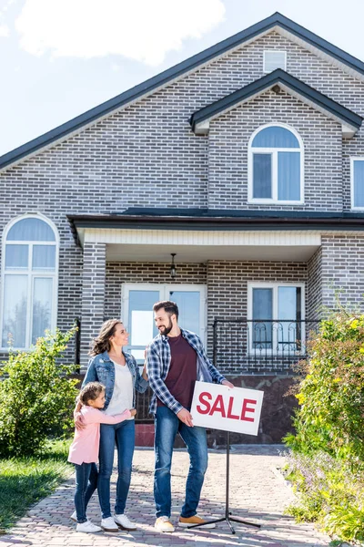 Famille debout devant la maison en vente — Photo de stock