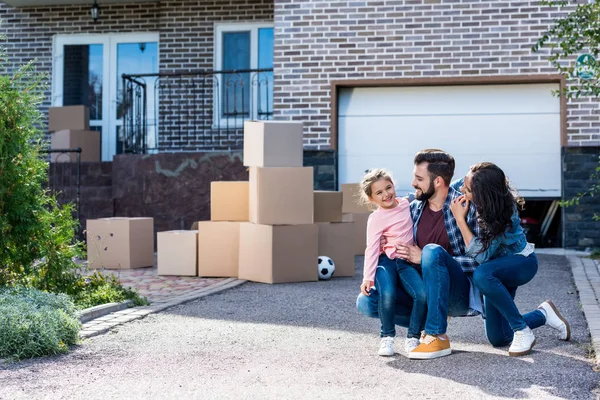 Familia sentada frente a una casa nueva — Stock Photo