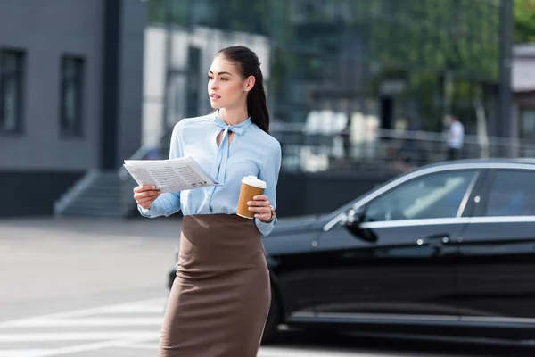 Empresaria sosteniendo periódico de negocios y café - foto de stock