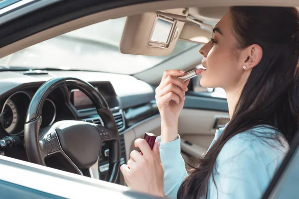 Mulher aplicando batom no carro — Fotografia de Stock