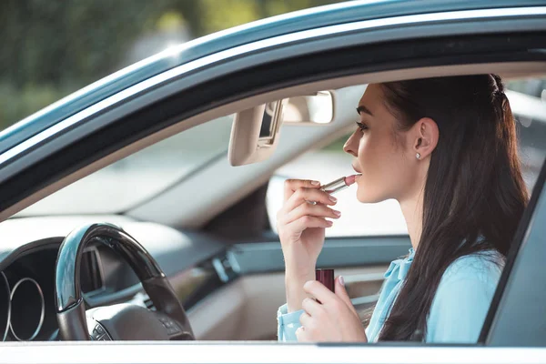 Frau trägt Lippenstift im Auto auf — Stockfoto