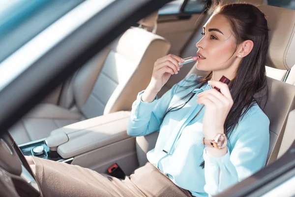 Frau trägt Lippenstift im Auto auf — Stockfoto