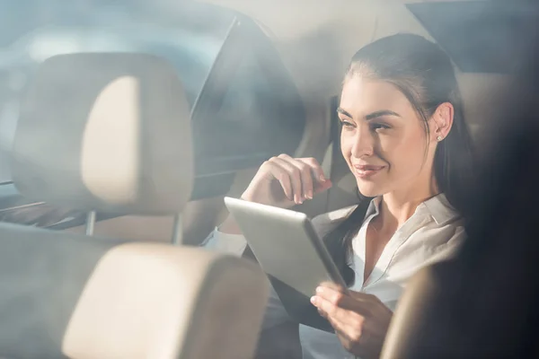 Femme en voiture avec tablette numérique — Photo de stock