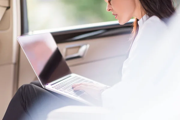 Woman using laptop in car — Stock Photo