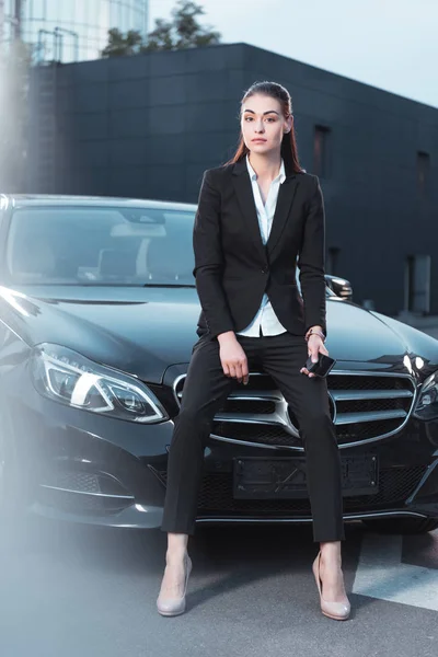 Mujer sentada en la capucha del coche - foto de stock