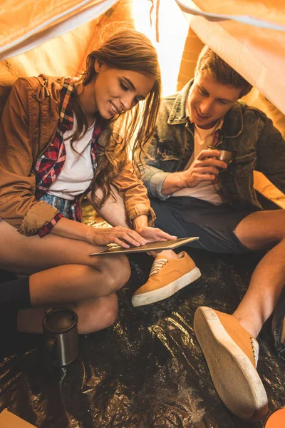 Couple using tablet in hiking tent — Stock Photo