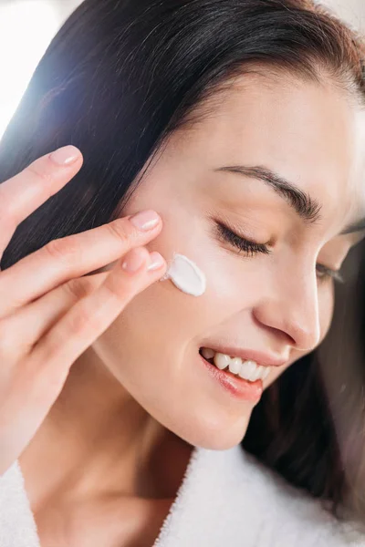 Mujer aplicando crema facial - foto de stock