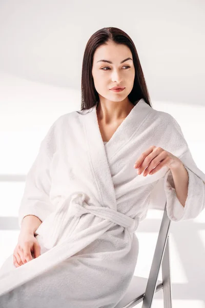 Jeune femme en peignoir relaxant sur chaise — Photo de stock