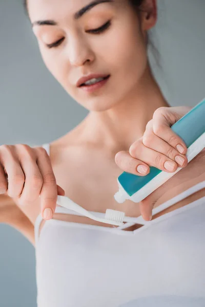 Mujer apretando pasta de dientes en el cepillo - foto de stock