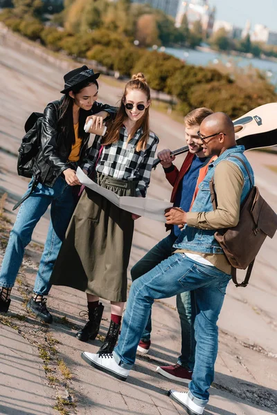 Multicultural friends choosing destination on map — Stock Photo