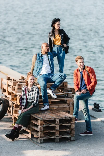 Multicultural friends resting on pier — Stock Photo