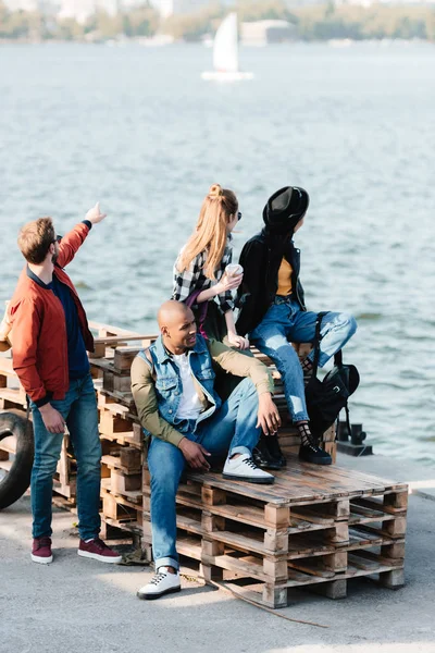 Amigos multiculturales descansando en el muelle - foto de stock