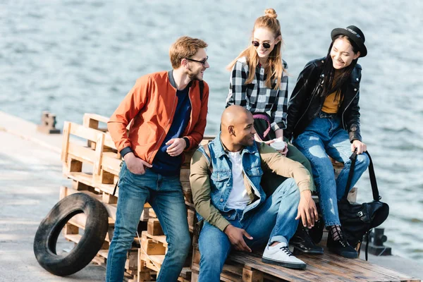 Multicultural friends resting on pier — Stock Photo