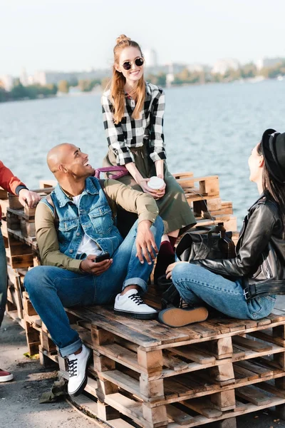 Multicultural friends resting on pier — Stock Photo