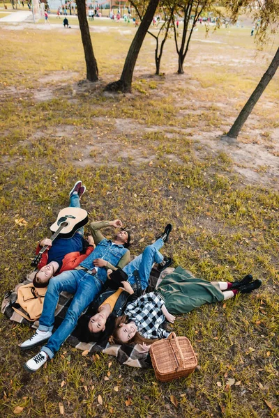 Amigos multiculturales descansando juntos sobre una manta - foto de stock