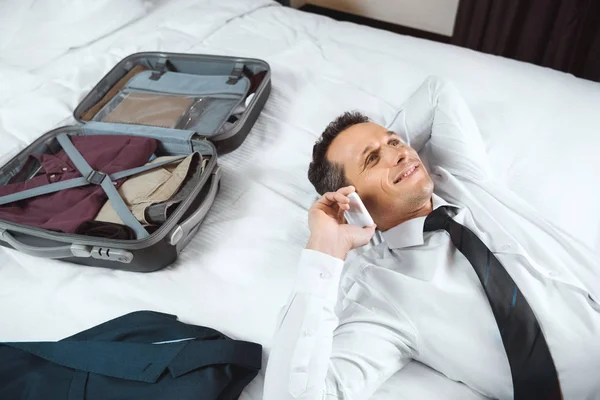Homme d'affaires parlant au téléphone sur le lit — Photo de stock