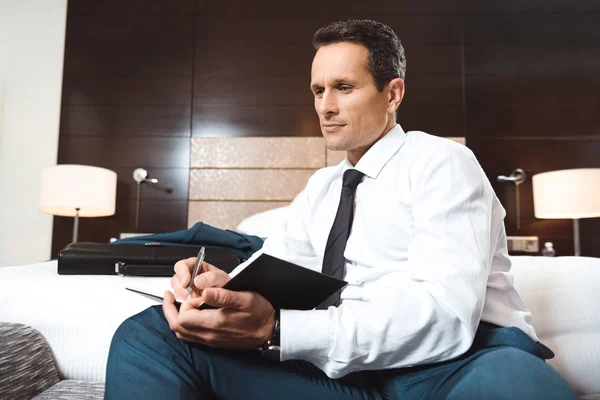 Hombre de negocios escribiendo en cuaderno - foto de stock