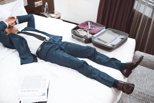 Exhausted businessman lying on bed — Stock Photo