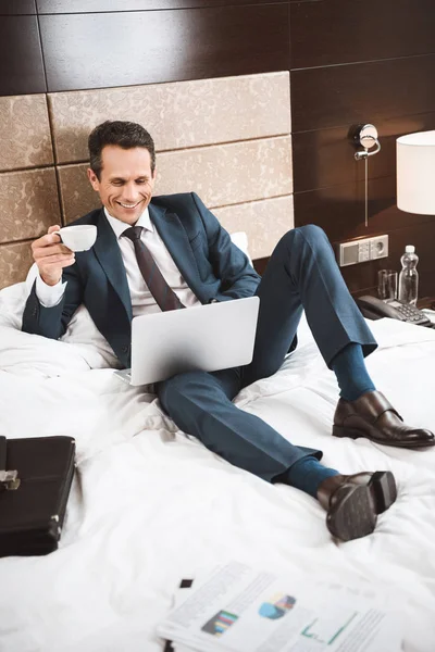 Homme d'affaires sur le lit travaillant avec ordinateur portable — Photo de stock