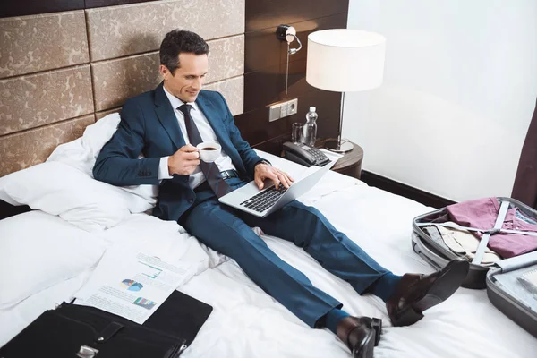 Homme d'affaires sur le lit travaillant avec ordinateur portable — Photo de stock