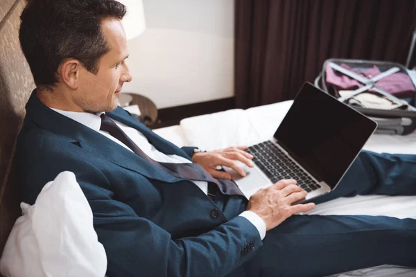 Hombre de negocios en la cama trabajando con el ordenador portátil - foto de stock