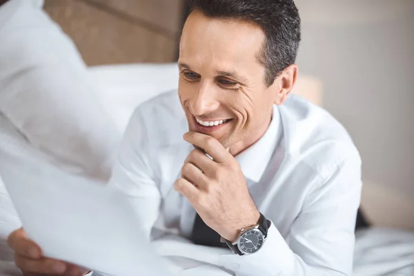 Businessman on bed reading paperwork — Stock Photo