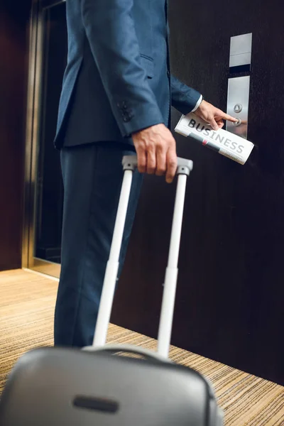 Hombre de negocios con maleta llamando ascensor - foto de stock