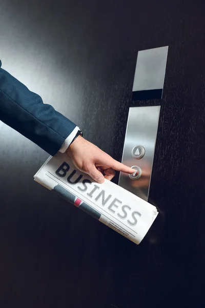 Hombre de negocios con periódico llamando ascensor - foto de stock