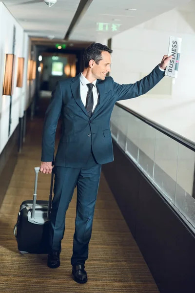 Uomo d'affari a piedi nel corridoio dell'hotel con valigia — Foto stock