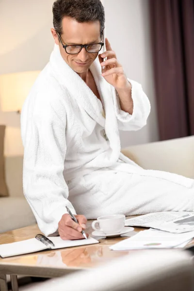 Businessman in bathrobe taking notes — Stock Photo