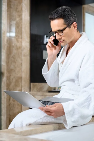 Geschäftsmann im Bademantel arbeitet mit Geräten — Stockfoto