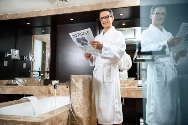 Businessman in bathrobe reading newspaper — Stock Photo