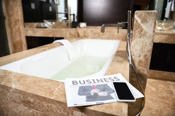 Business newspaper on bathtub — Stock Photo