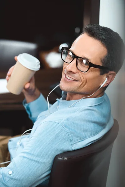 Businessman in headphones with coffee cup — Stock Photo