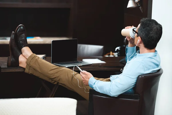 Businessman in headphones drinking coffee — Stock Photo