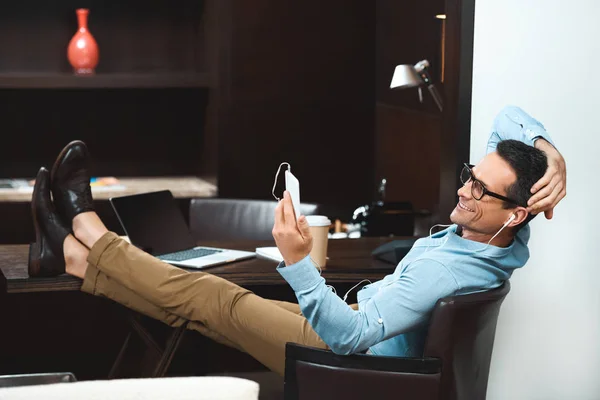 Hombre de negocios en la lectura de auriculares desde el teléfono inteligente - foto de stock