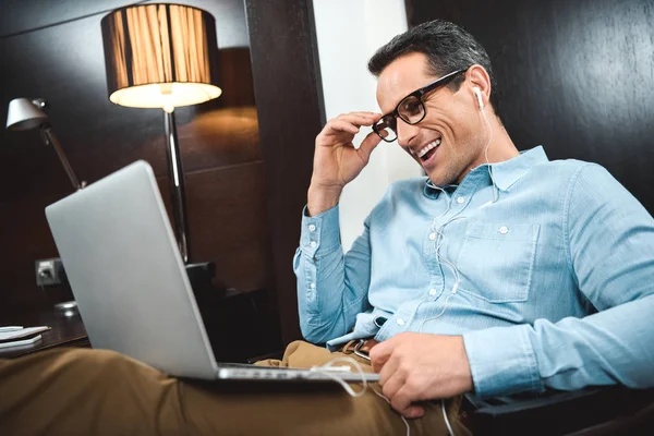 Homem de negócios rindo em fones de ouvido usando laptop — Fotografia de Stock