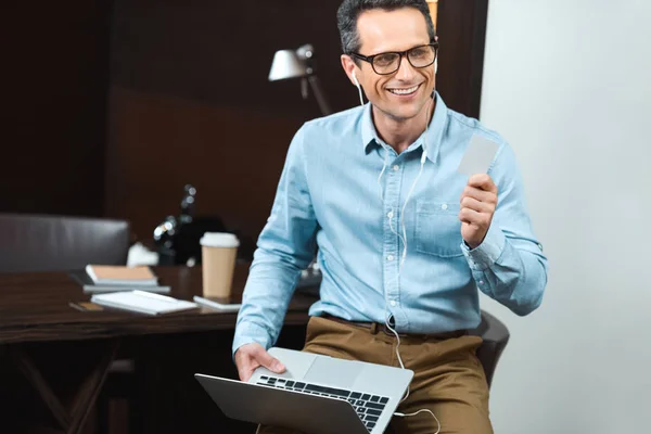 Empresário segurando cartão de crédito e laptop — Fotografia de Stock