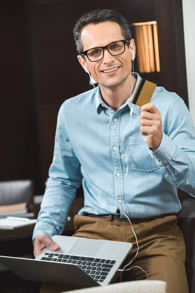 Hombre de negocios con tarjeta de crédito y portátil - foto de stock