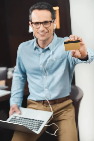 Empresário segurando cartão de crédito e laptop — Fotografia de Stock