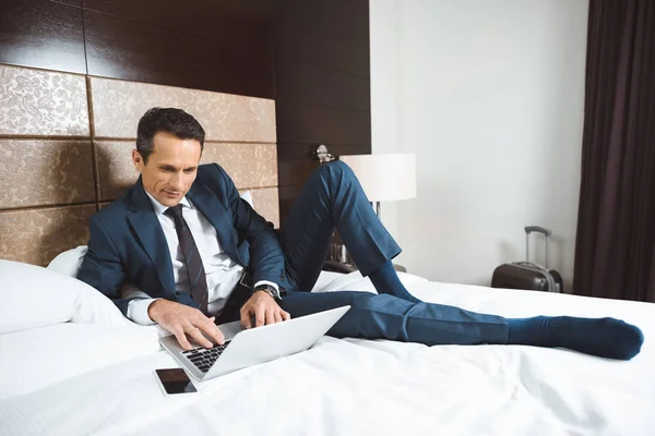 Бізнесмен на ліжку використовує ноутбук — стокове фото