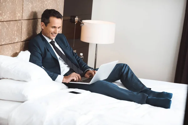 Бізнесмен на ліжку використовує ноутбук — стокове фото