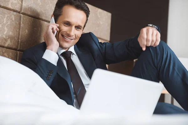 Businessman on bed talking on phone — Stock Photo