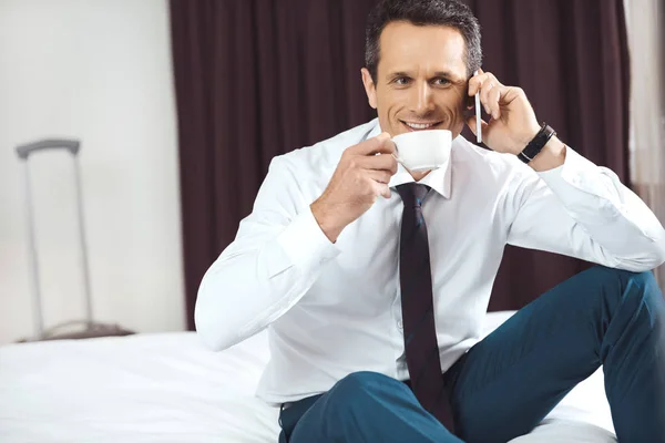 Бизнесмен пьет кофе и разговаривает по телефону — стоковое фото